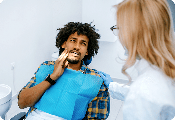 man with tooth pain sitting with dentist